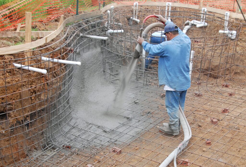 A builder sprays gunite to create a suburban pool