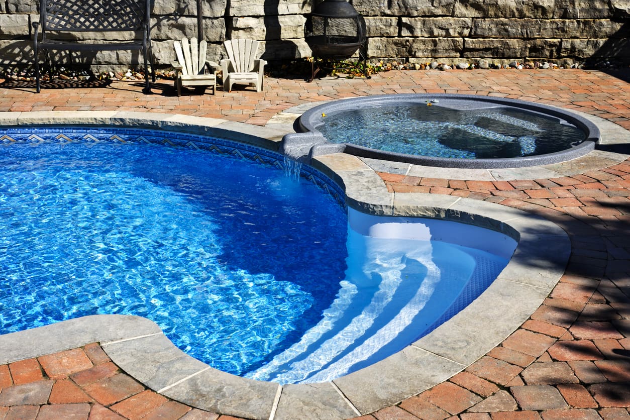 fiberglass pool with a spa installed in the backyard