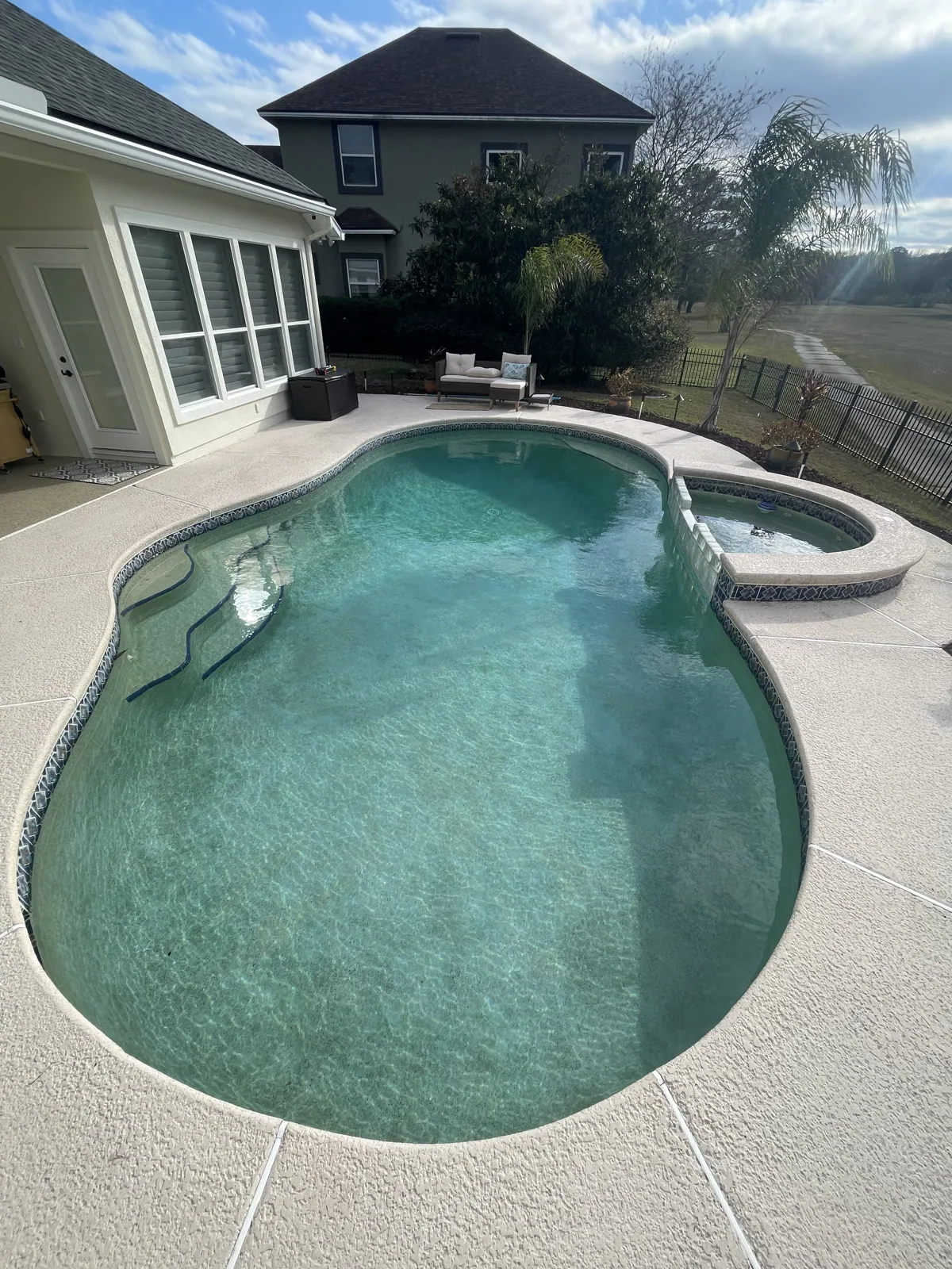 Custom freeform pool with a raised spa and spillover overlooking a lake