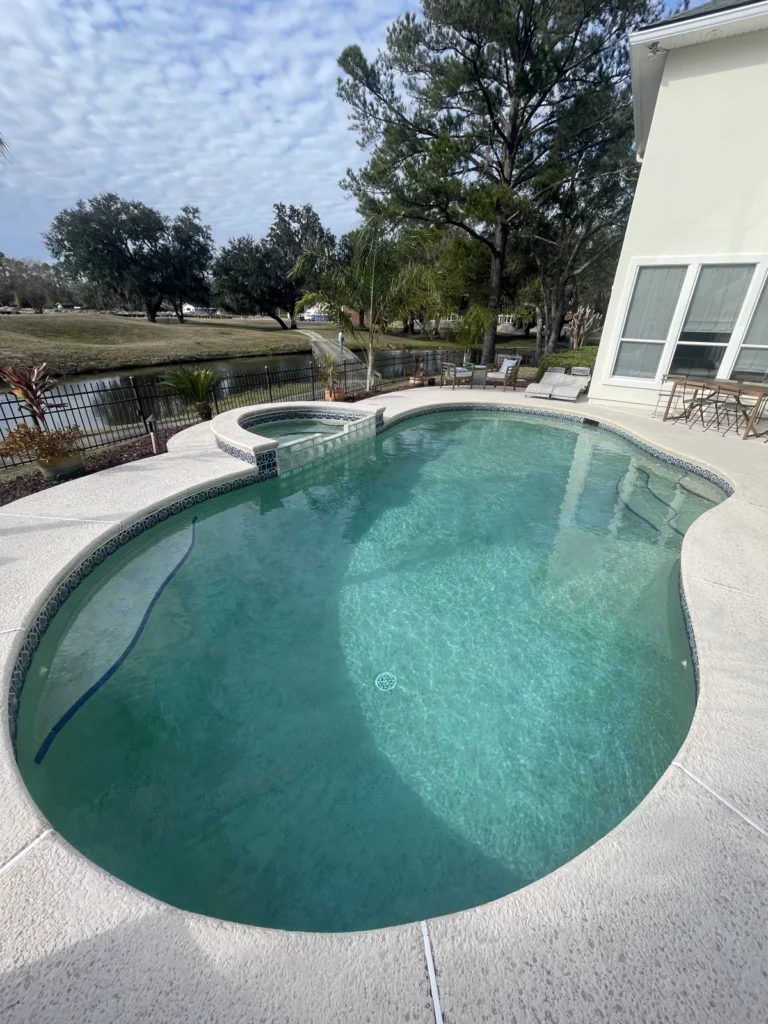 Freeform custom pool and spa with a lake view beyond the deck