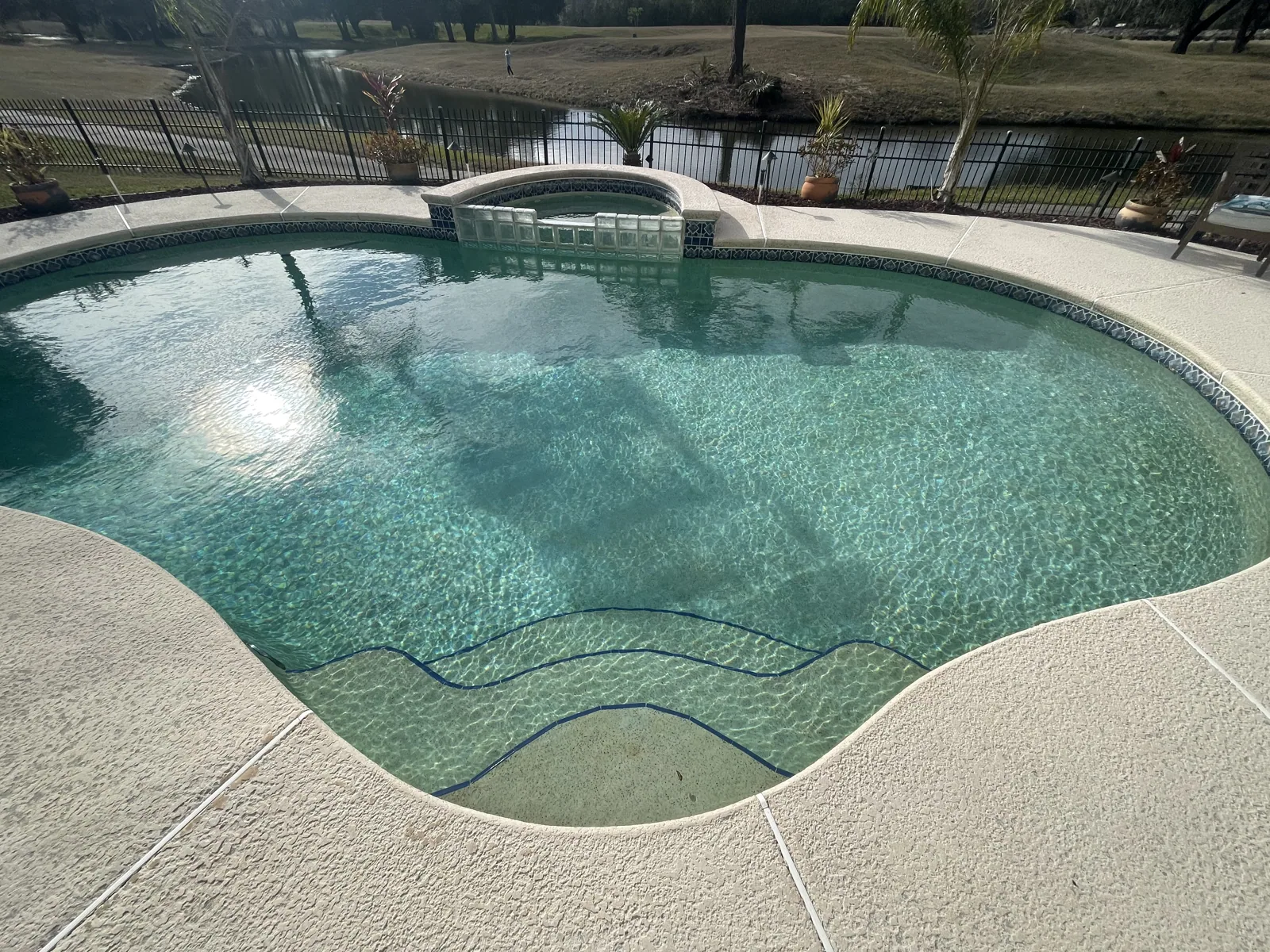 Custom concrete pool and spa with decorative tile and a curved edge