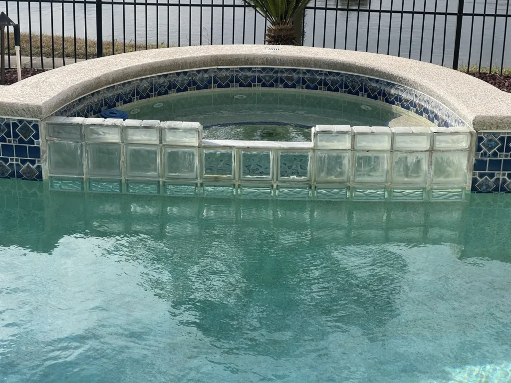 Raised spa spilling into a custom pool, with a glass tile band across the face