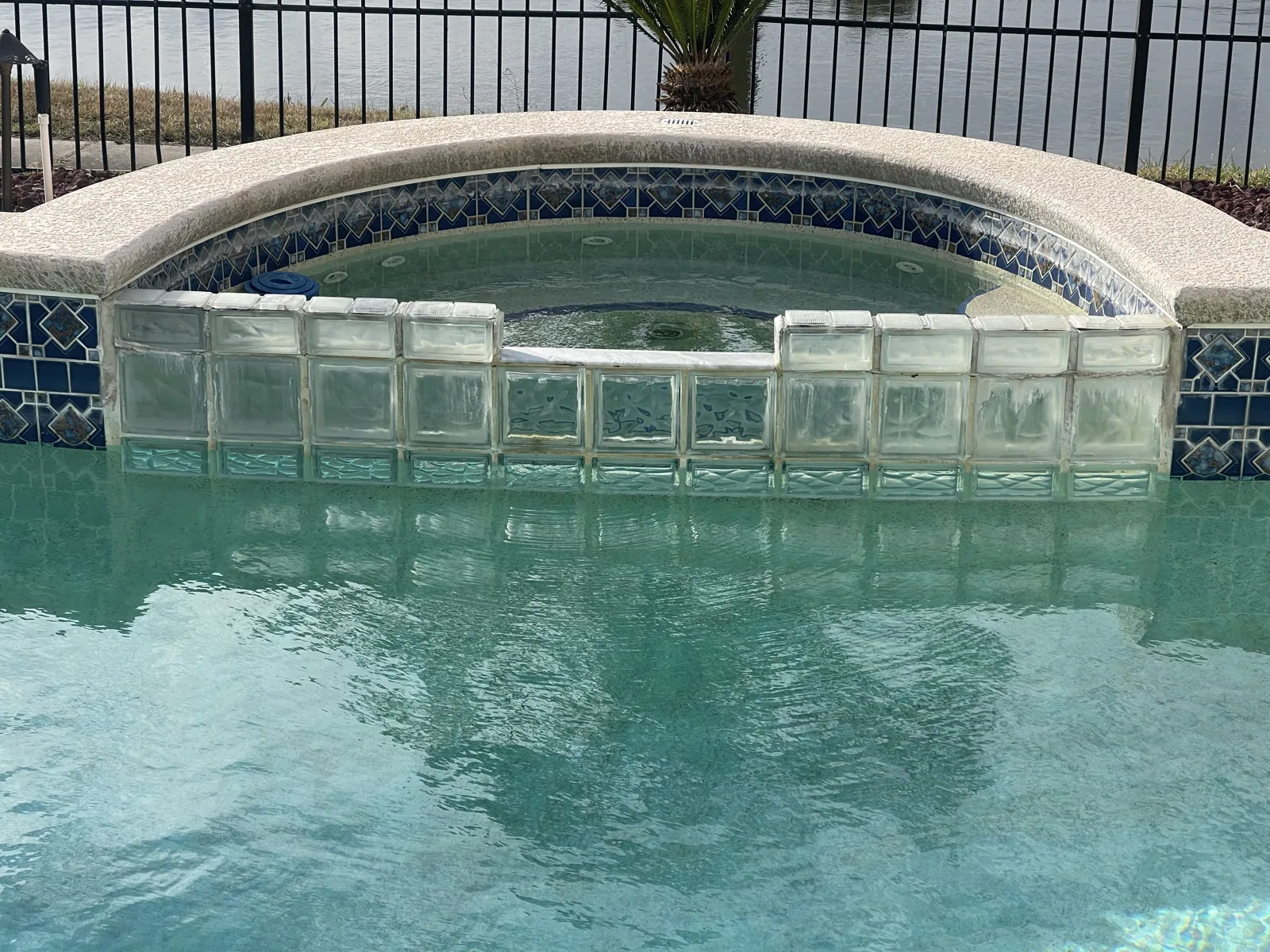 Raised spa spilling into a custom pool, with a glass tile band across the face