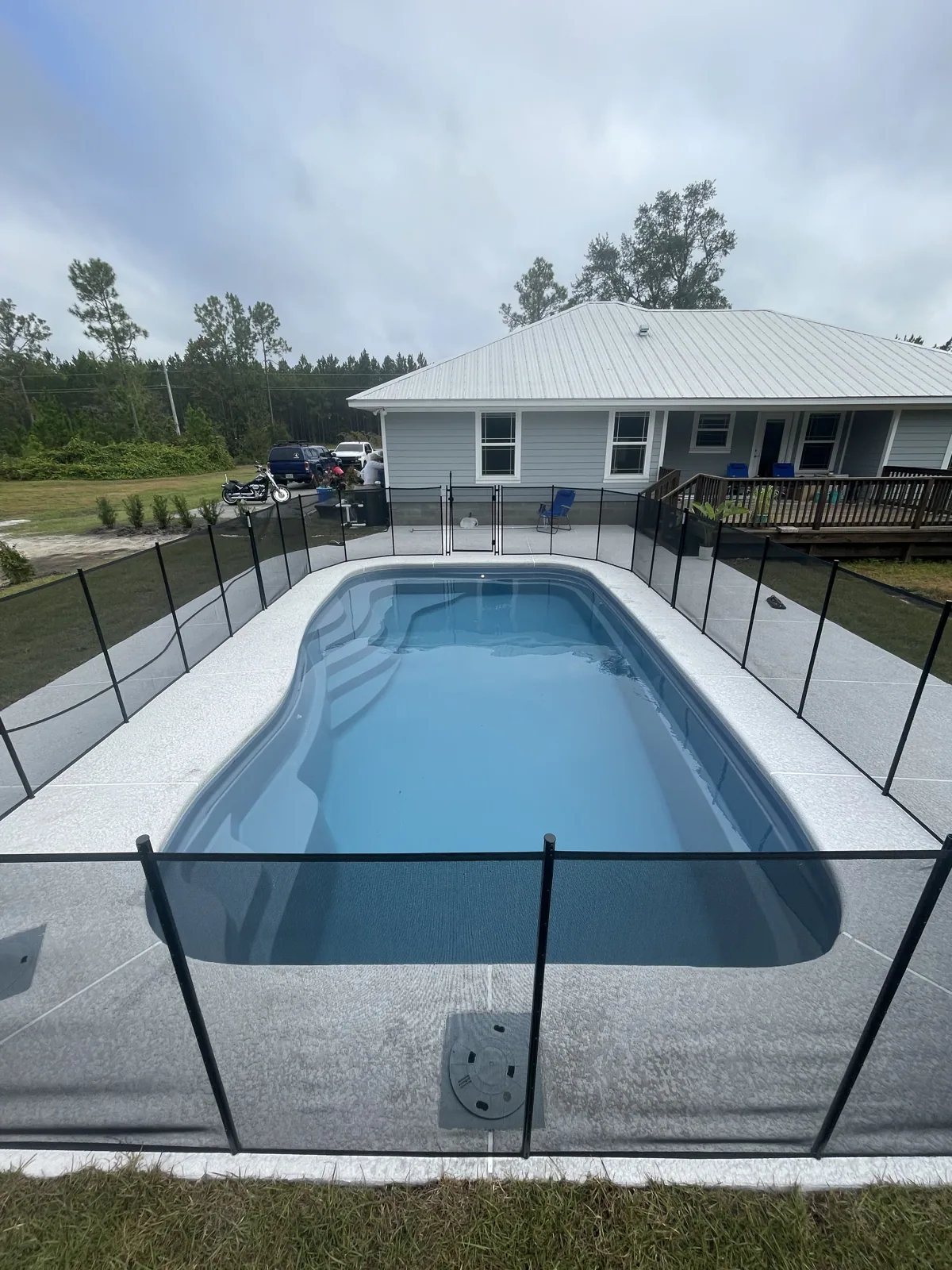 Completed fiberglass pool surrounded by open lawn and a new home