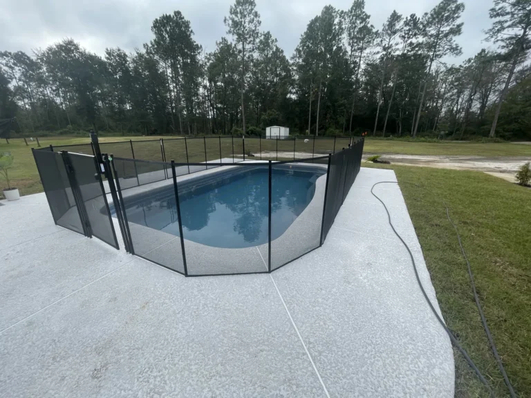 Fiberglass pool with blue water seen across the concrete deck