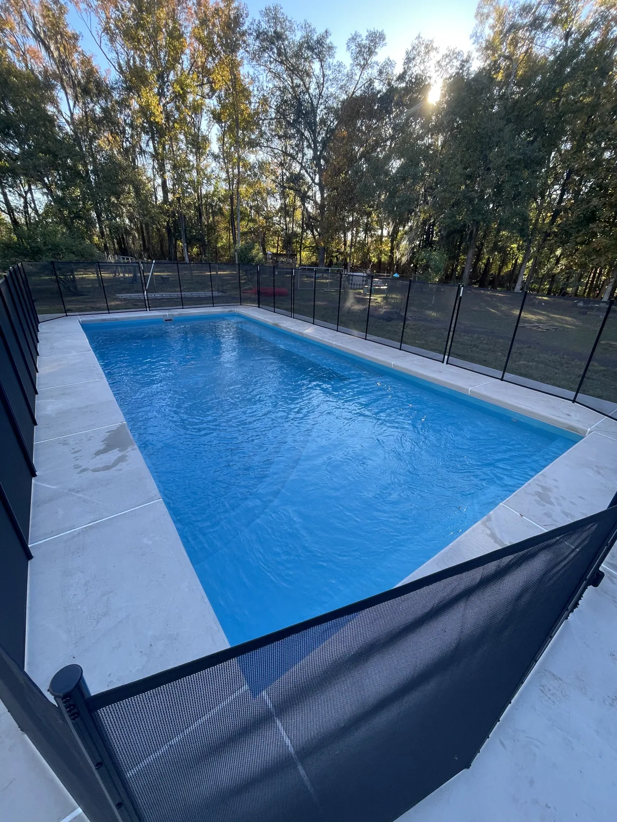 Completed fiberglass pool installation with safety fencing and finished deck