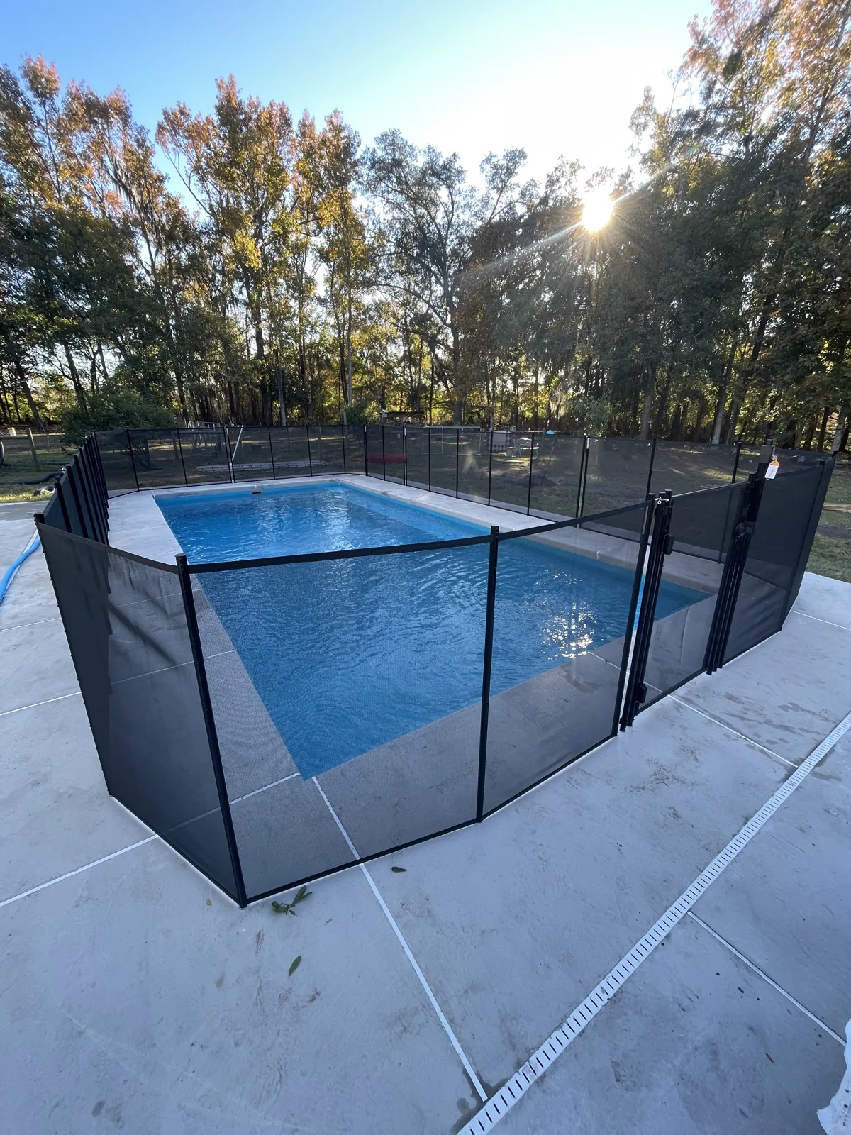 Finished fiberglass pool enclosed by a removable mesh safety fence