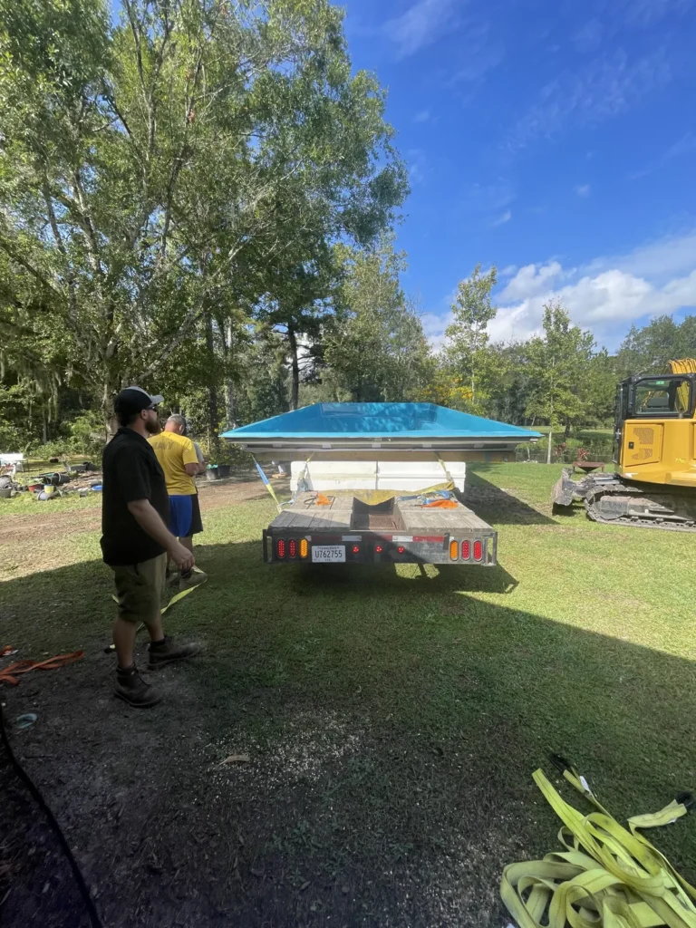 Fiberglass pool shell arriving on a trailer for installation