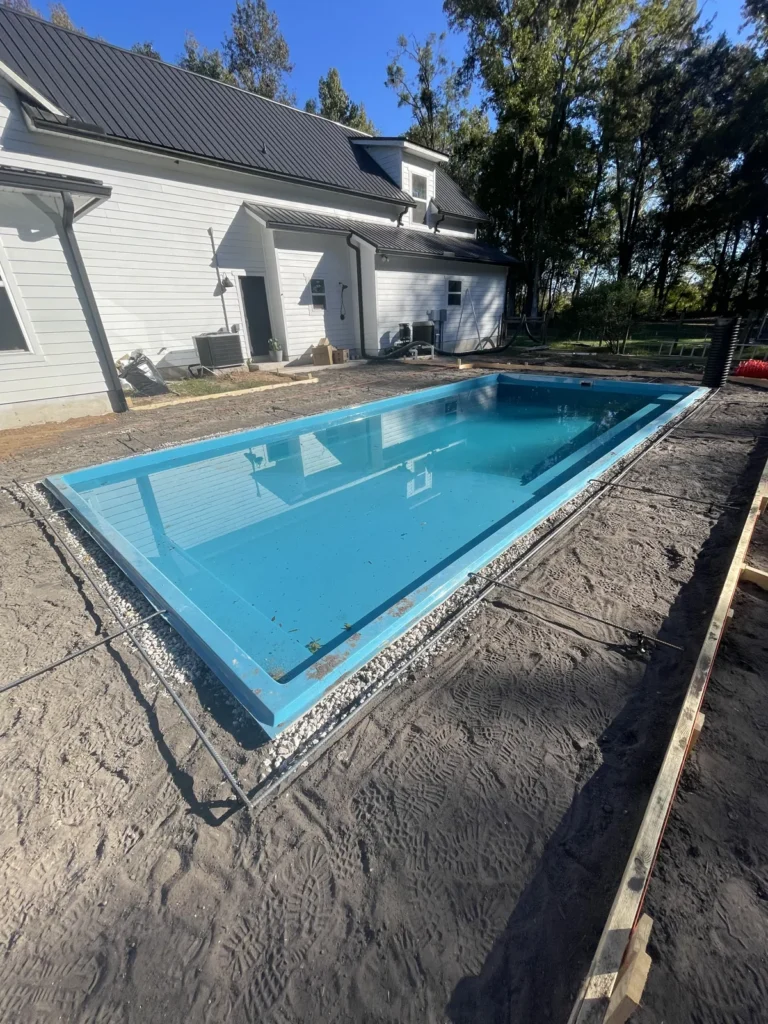 Fiberglass pool being filled with water after the shell was set and backfilled