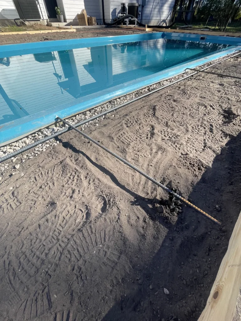 Partially filled fiberglass pool with the surrounding area prepared for decking