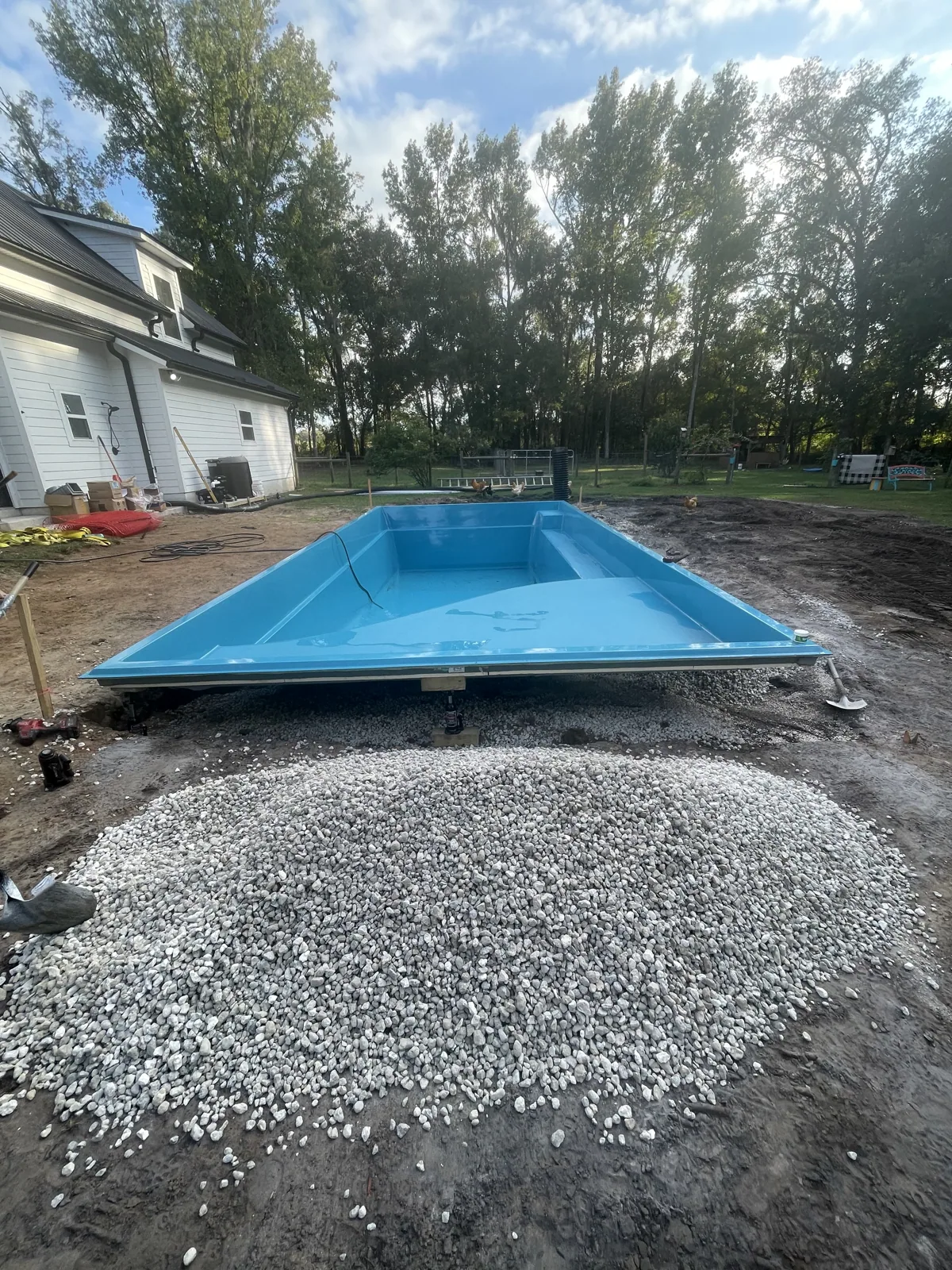 Fiberglass pool shell being lowered into the excavated hole