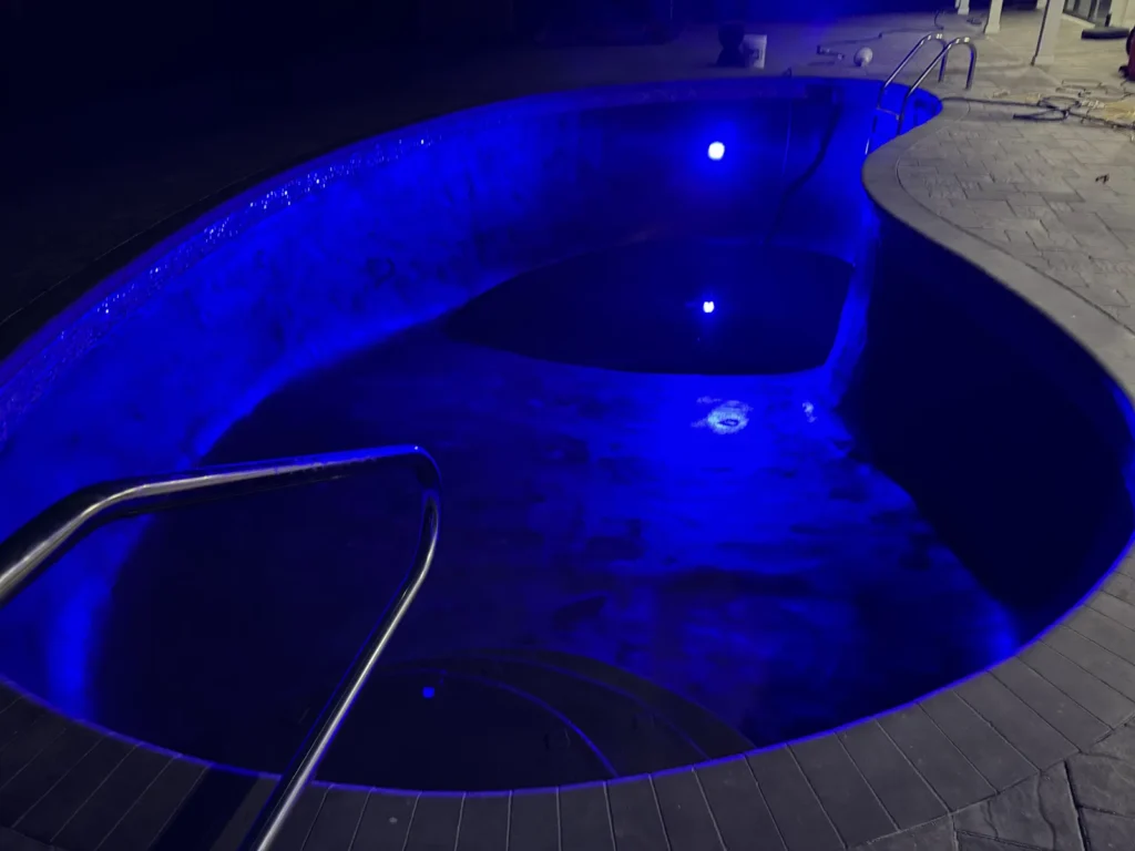 Pool lit blue at night with color-changing LED pool lighting