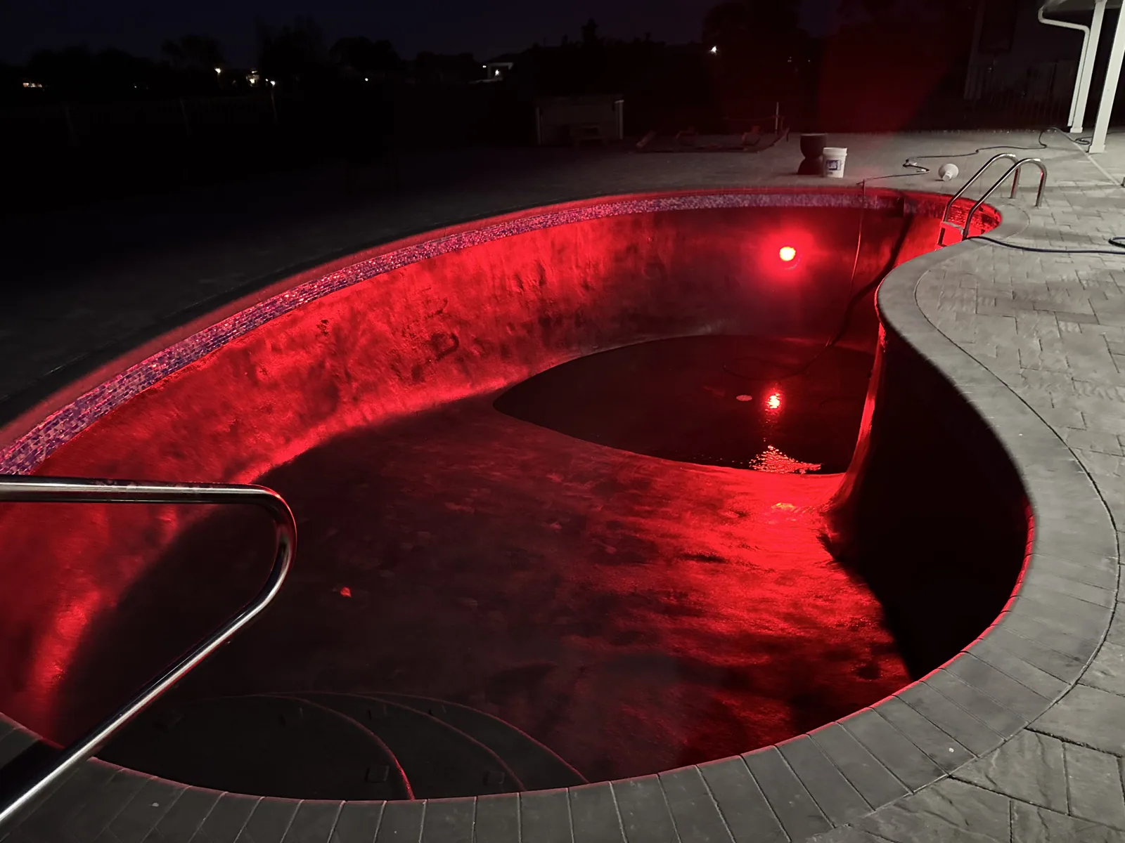 Pool lit red at night with color-changing LED pool lighting