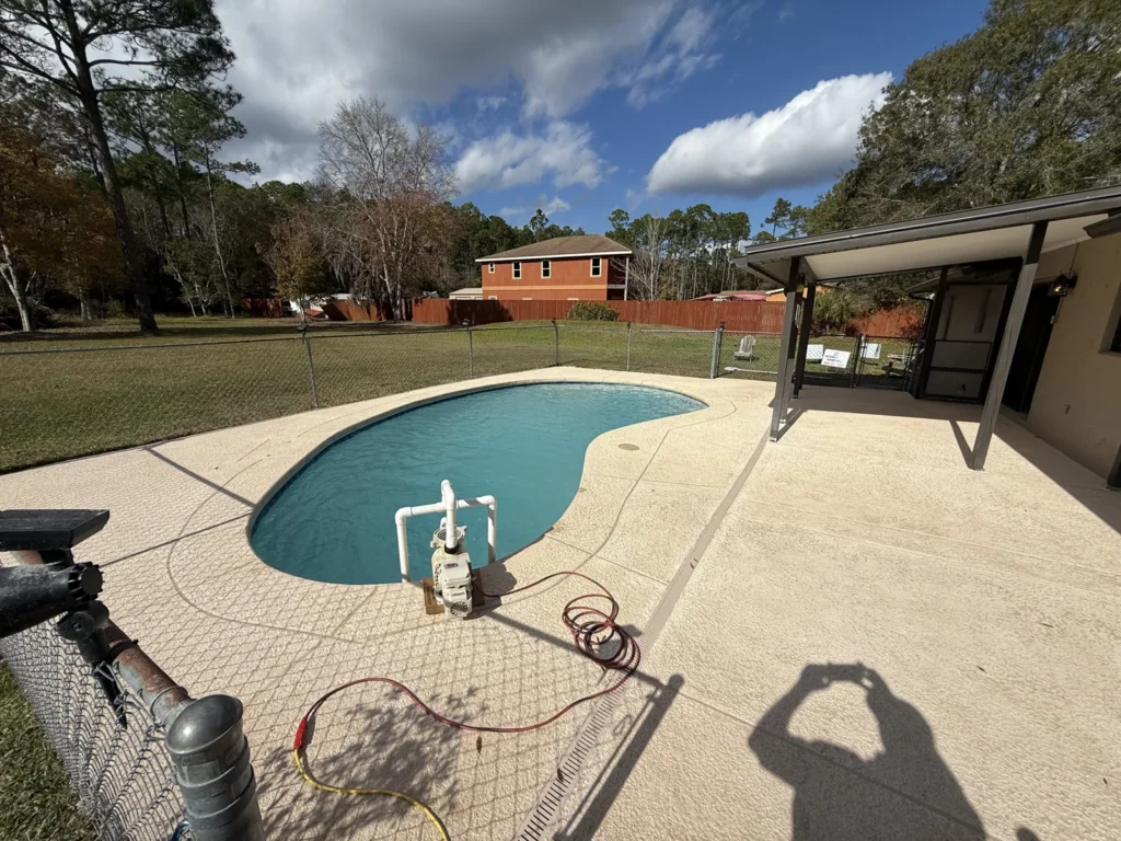 Completed concrete pool remodel seen from the far corner of the property