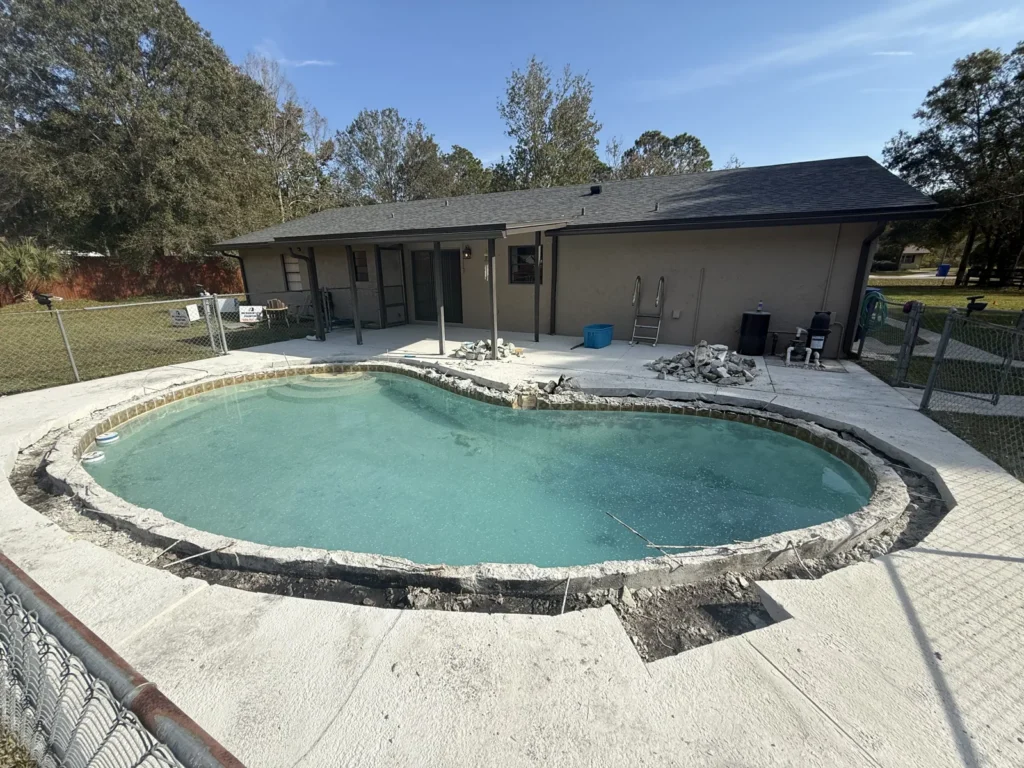 Wide view of a dated concrete pool in Northeast Florida before its remodel began