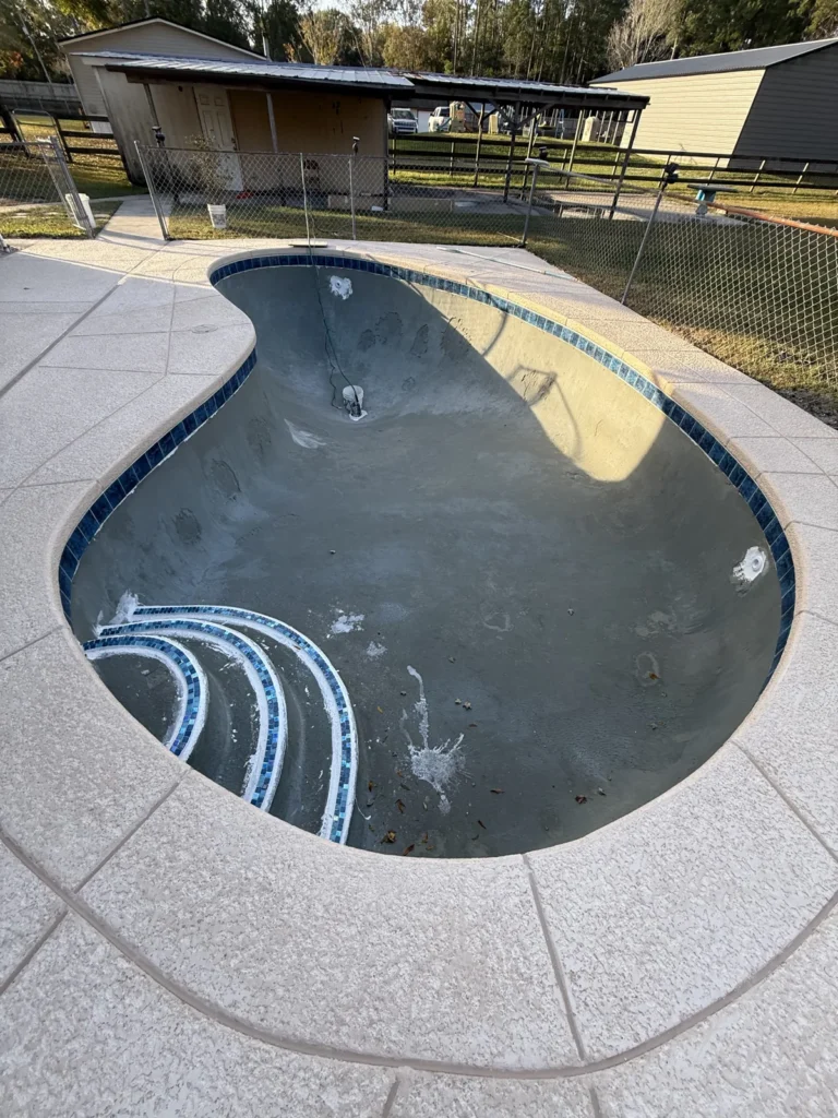 Remodeled pool with new coping and waterline tile installed, waiting to be filled