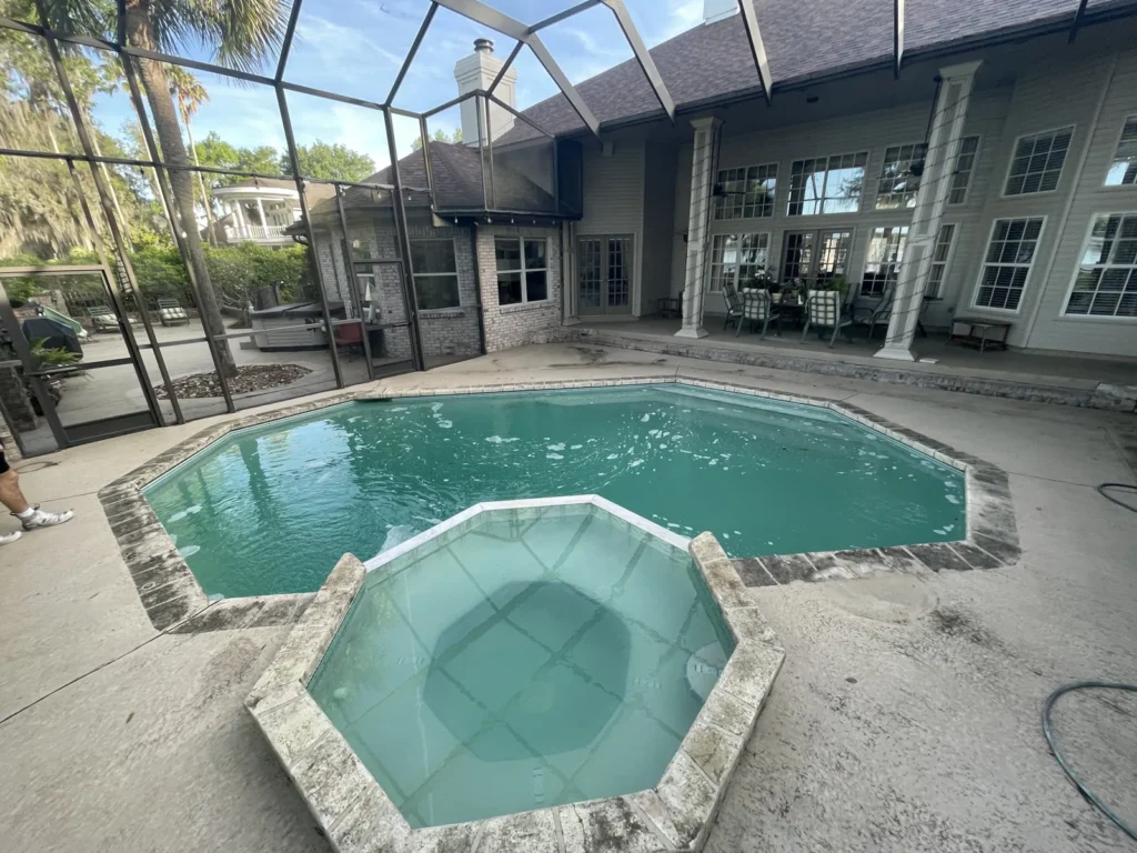 Screened lanai with a pool and raised spa beside the house